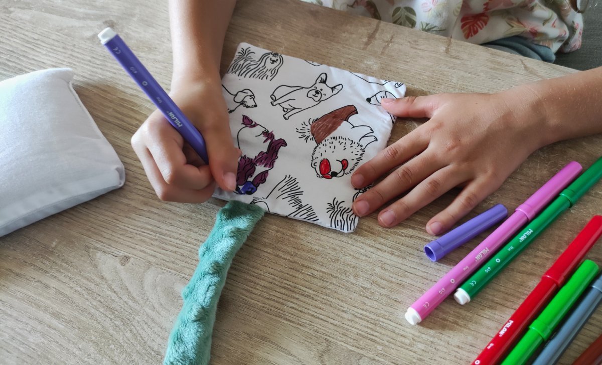 Enfant coloriant la housse lavable de sa bouillotte sèche