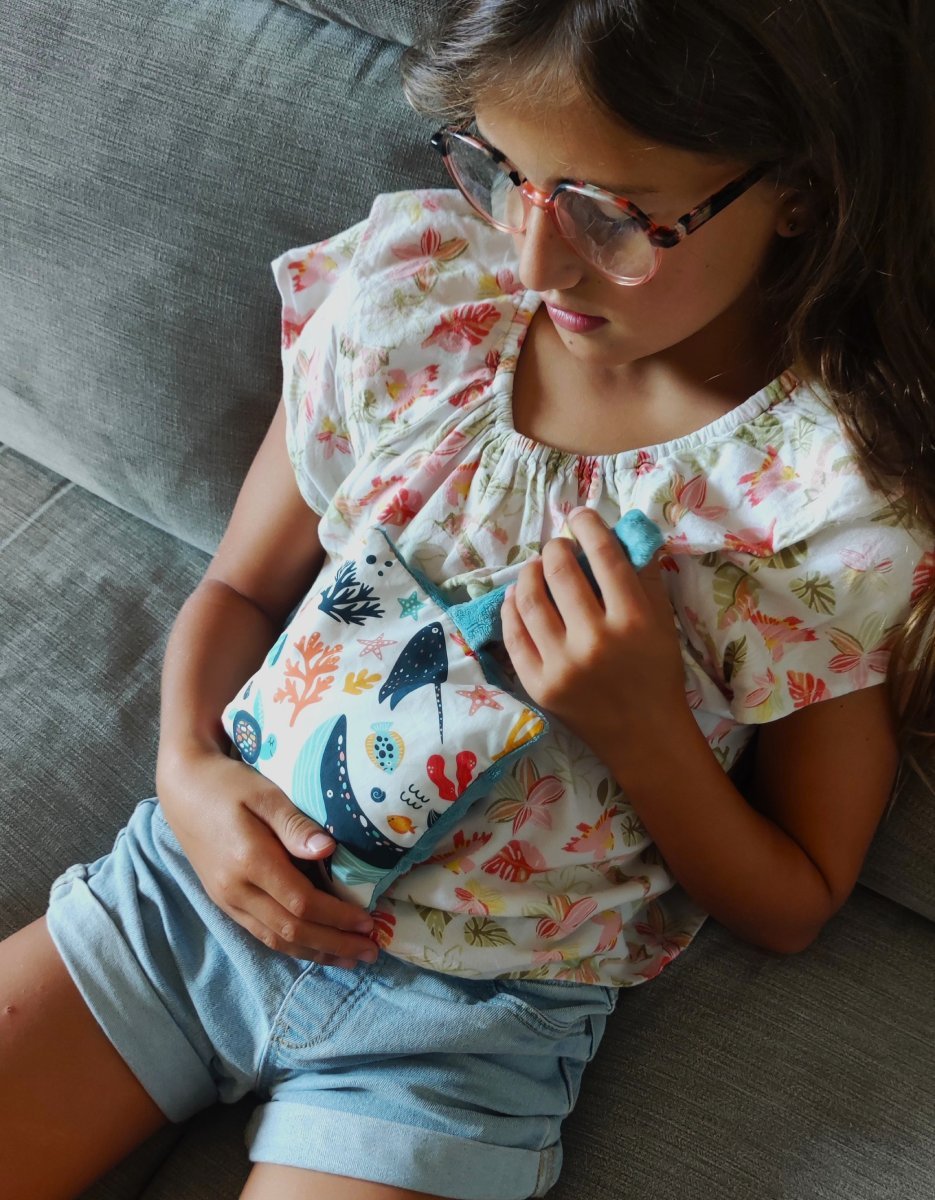Enfant avec une bouillotte sèche en graines de lin contre elle