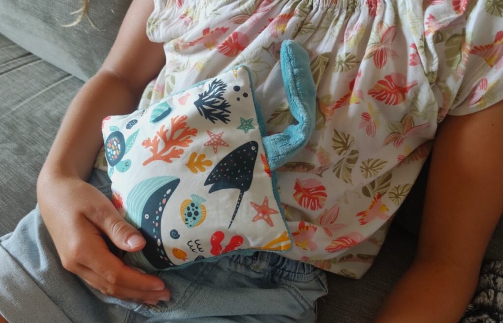Enfant tenant une bouillotte sèche douce sur un canapé