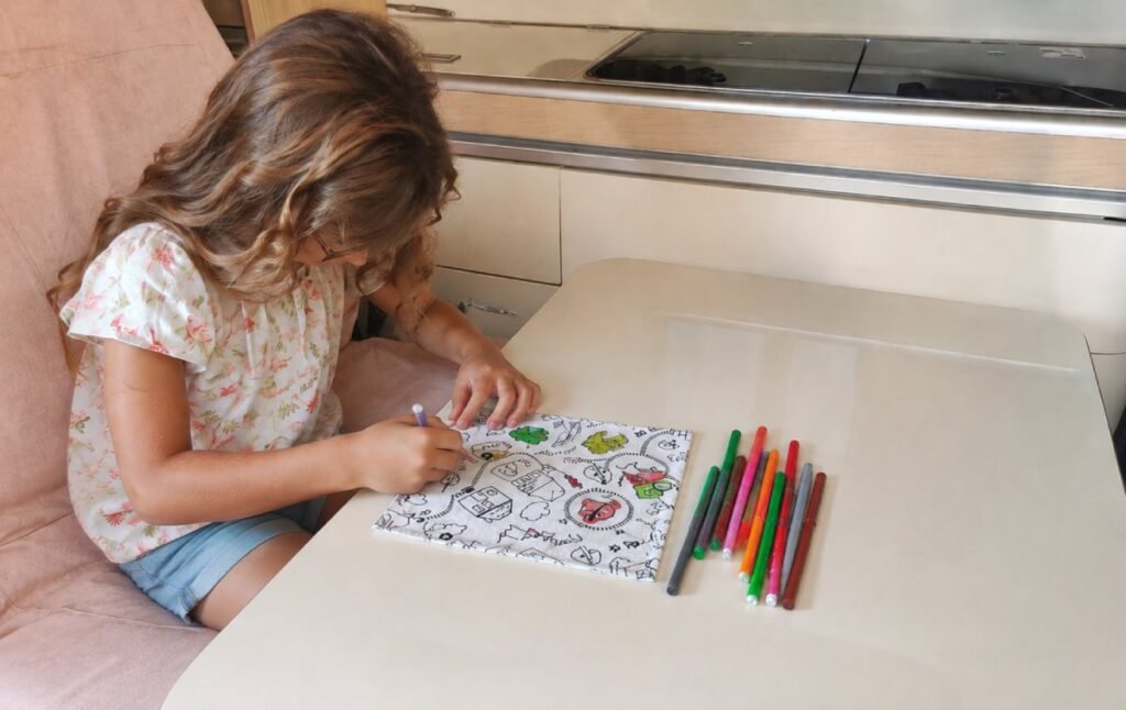 Enfant utilisant un kit de coloriage lavable nomade à la table d’un van